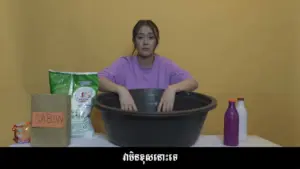 Young woman mixing ingredients in a large bowl, surrounded by bags of flour and colorful containers against a yellow backdrop.