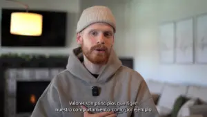 Man with a beige beanie and hoodie speaking in a modern living room with a soft color palette and cozy decor.