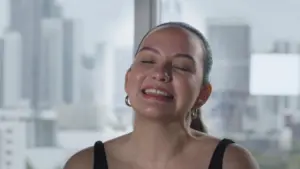 Smiling woman in a black top with city skyline in the background, reflecting happiness and urban lifestyle.