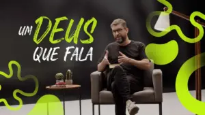 A speaker sits in a modern chair, discussing the theme "Um Deus Que Fala" against a vibrant black and green backdrop.