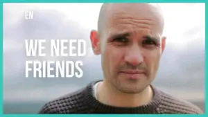 Bald man with a serious expression against a cloudy background, accompanied by the text "We Need Friends."