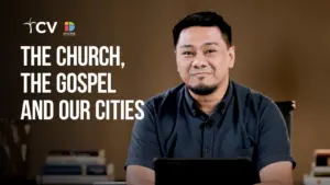 Man sitting at a desk with a tablet, discussing the church, the gospel, and urban life in a modern setting.