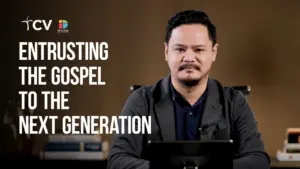 A speaker presents a message about passing the gospel to future generations, with books in the background.