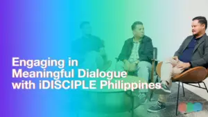 Two men seated in a modern setting discussing impactful dialogues with iDISCIPLE Philippines, featuring colorful gradient background.