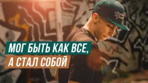 Young man in a cap standing against an abstract graffiti wall, reflecting on individuality and self-identity.