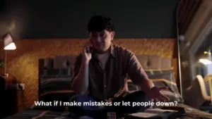 A contemplative man sitting on a bed, holding a phone, expressing anxiety about making mistakes and disappointing others.