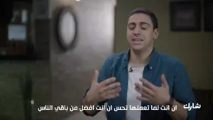 Person gesturing enthusiastically in a modern indoor setting, conveying a motivational message in Arabic.