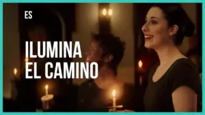 Two people smiling with candles in a warmly lit setting, accompanied by the text "Ilumina el Camino."