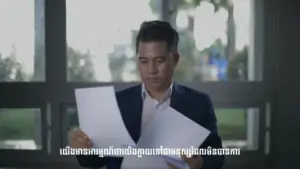 Man examining documents in an office setting, showcasing focus and contemplation. Natural light through large windows.