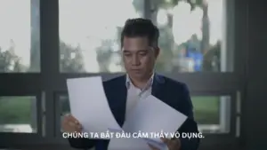 A man in a suit examines documents, reflecting on feelings of frustration and confusion in a modern office setting.