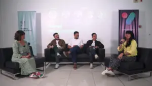 Panel discussion featuring four speakers sitting on a couch, engaging with the audience in a modern setting.