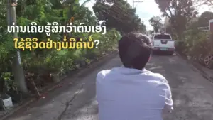 A person sitting on a motorcycle looking down a tree-lined road with a car in the distance, exploring local scenery.