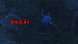 A person lying on rocky terrain at night, with bold red text in Thai overlaying the image.