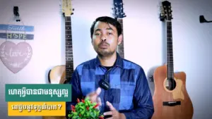 Man speaking in front of guitars, promoting a message of hope with a small plant in hand.