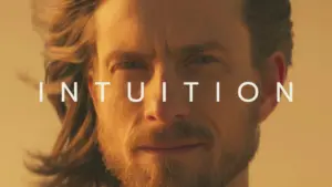 Close-up of a man with flowing hair, conveying a sense of confidence and introspection, with the word "INTUITION" displayed prominently.