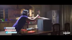 A woman in a purple shirt unboxes a new appliance in a cozy kitchen, with plates and a cup on the table.