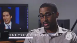 A man speaks in front of a computer screen displaying a tutorial, emphasizing self-learning through online resources.