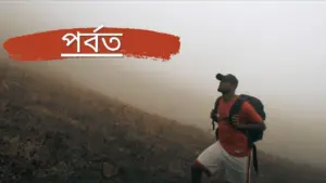 Hiker in a foggy mountainous landscape, showcasing determination and adventure with a backpack and vibrant red shirt.