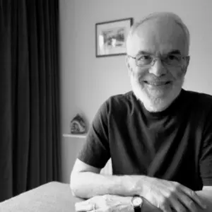 Smiling elderly man with glasses and a beard sits at a table, showcasing a warm and inviting atmosphere.