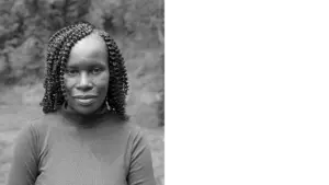 Black and white portrait of a woman with braided hair, smiling gently in a natural outdoor setting.