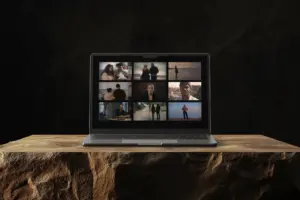 Laptop displaying a collage of video clips on a wooden surface against a dark background.