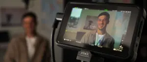 Close-up of a camera monitor displaying a smiling man in a studio setting, showcasing focus and lighting techniques.