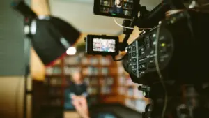 Cameras focus on an interview setup in a cozy library, featuring a well-lit subject ready for filming.