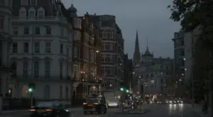 Dimly lit city street at dusk, showcasing historic buildings and traffic lights in a bustling urban setting.