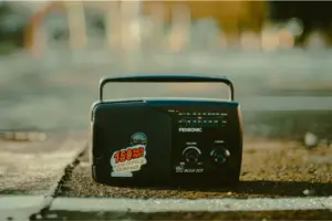 Vintage portable radio on a city street, showcasing retro design and urban setting with a blurred background.